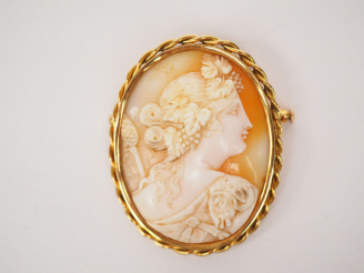 Vente aux enchères 	Broche ornée d’un camée coquille, à décor de profil de femme à l’anti