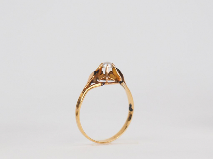 Bague en or jaune, ornée en son centre d'une perle en cabochon. TDD. 5