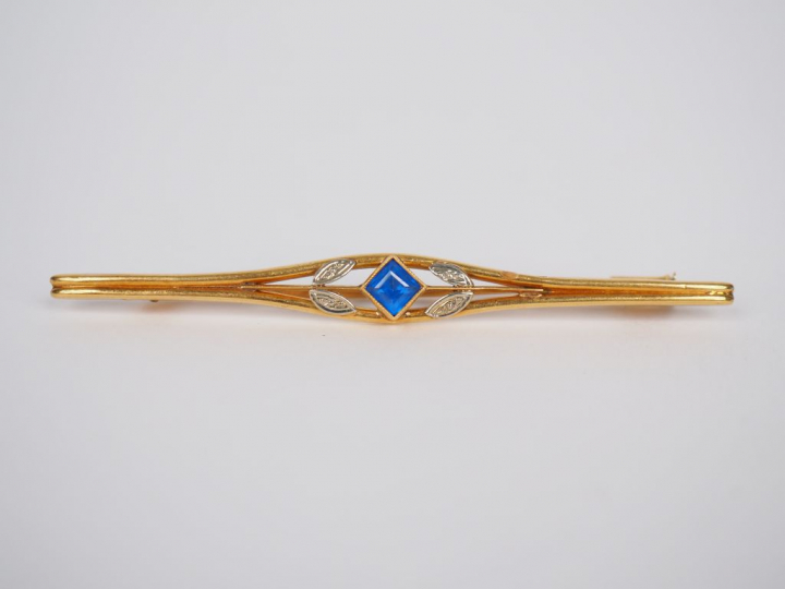 Broche barrette en or jaune, ornée en son centre d'une pierre bleue. L