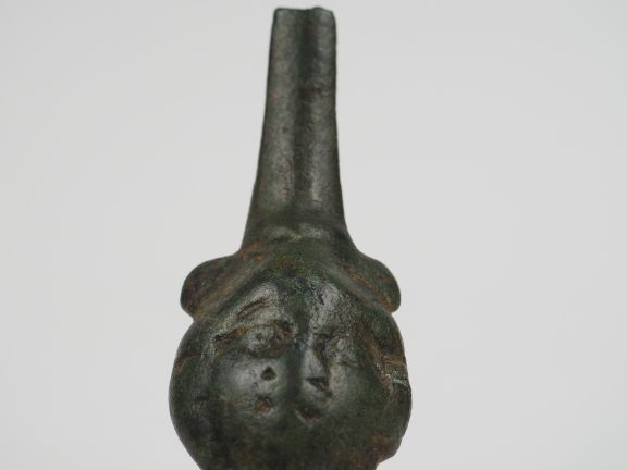 Fragment d’une anse en bronze décorée d’une tête. H. : 9 cm.