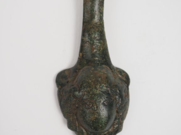 Fragment d’anse en bronze décorée d’une tête de méduse en applique. H.