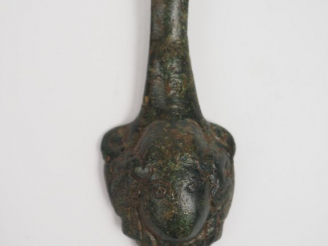 Vente aux enchères Fragment d’anse en bronze décorée d’une tête de méduse en applique. H.