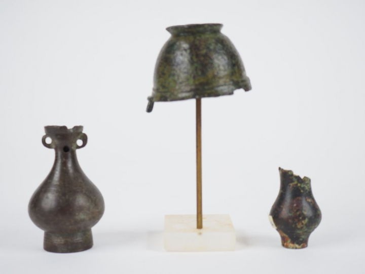 Trois vases votifs en bronze. Accidents.  H. : 7 cm, 4.5 cm, 4 cm.