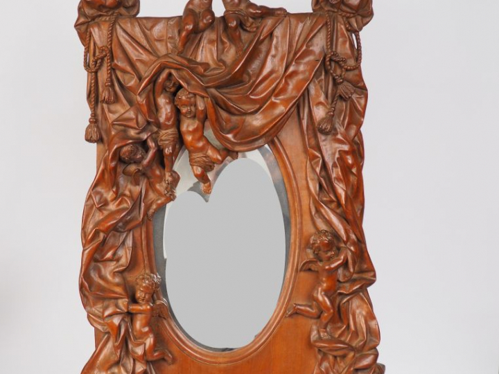 Miroir XIXème en bois sculpté à décor d'amours dans une draperie. Dim.