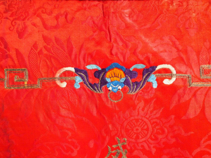 Grand panneau en soie rouge brodé aux fils polychromes et anciennement