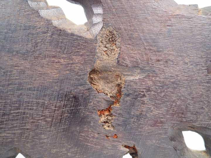 Corniche en bois sombre, sur lequel est assis un personnage aux vêteme