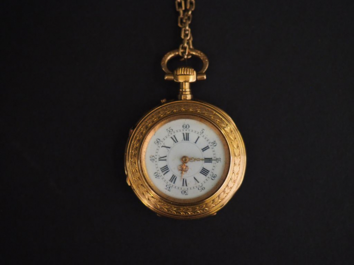 Montre de col en or jaune.  Le revers à décor de monogramme appliqué. 