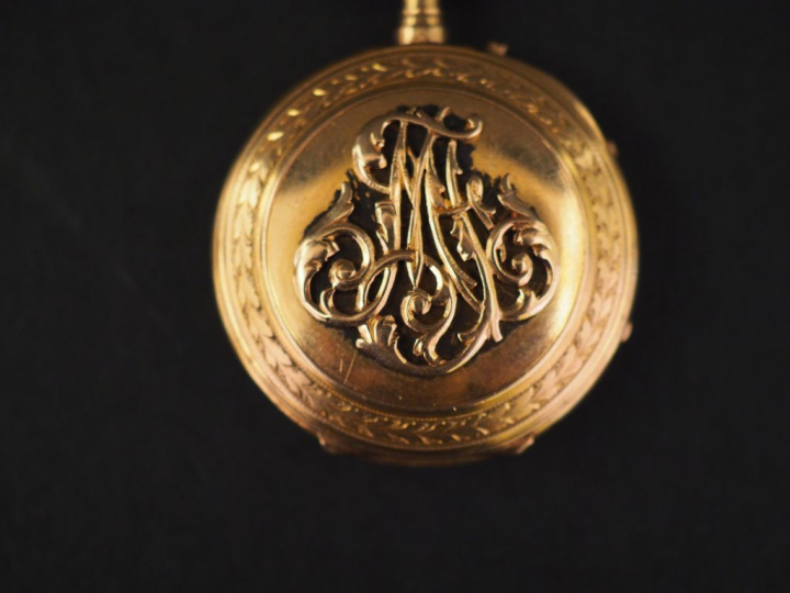 Montre de col en or jaune.  Le revers à décor de monogramme appliqué. 