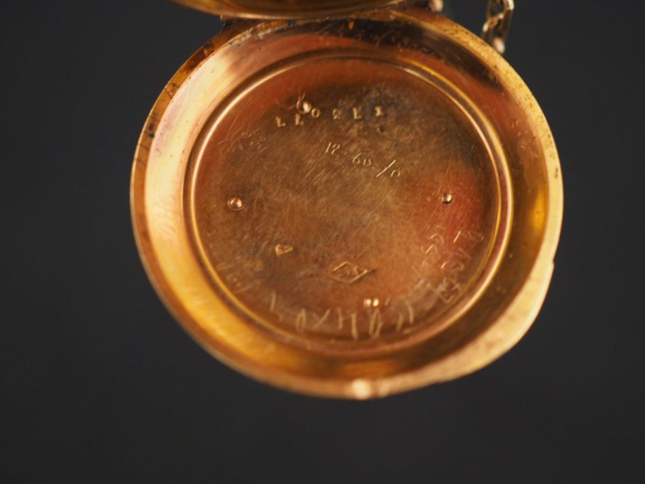 Montre de col en or jaune.  Le revers à décor de monogramme appliqué. 