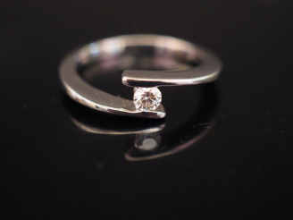 Vente aux enchères Bague en or blanc de forme stylisée, sertie d'un petit diamant de 0,13