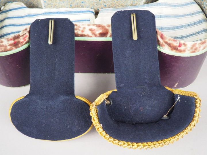 Longue boite en cartonnage vert contenant une épaulette et une contre 