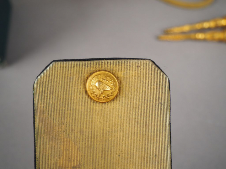 Boite en cartonnage vert contenant une épaulette et une contre épaulet