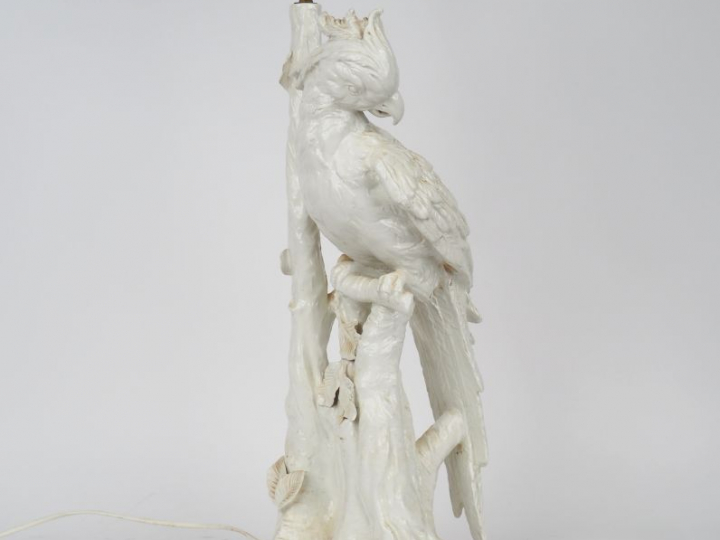 Lampe en porcelaine blanche figurant un perroquet branché. H. 58,8 cm.