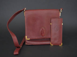 Vente aux enchères MUST DE CARTIER. Pochette en cuir marron H. 21 cm (état d'usage)  on y