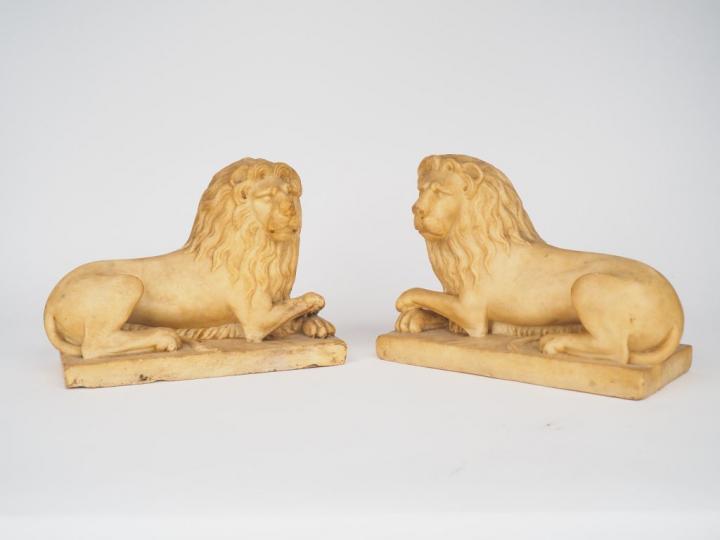 Paire de lions en albâtre sculpté en ronde-bosse. Couchés, les antérie