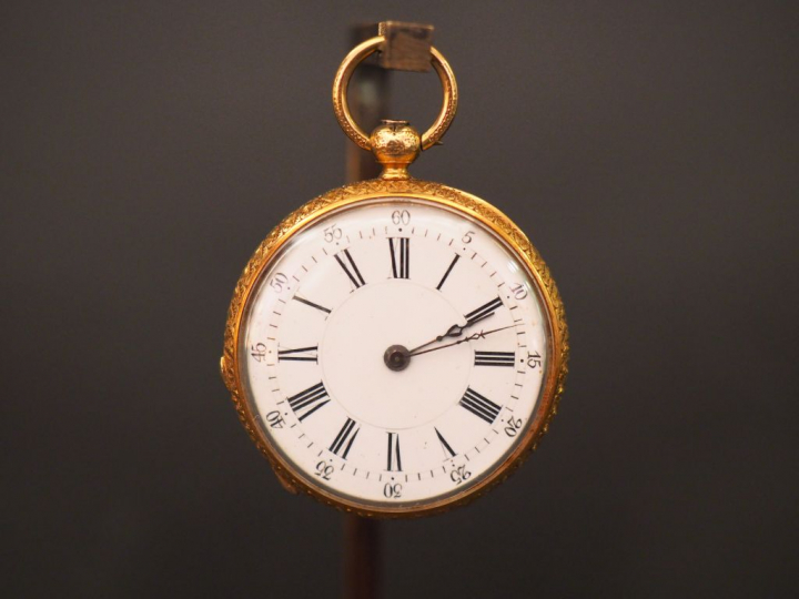 Montre de col en or jaune et émail noir. Le revers à décor de monogram