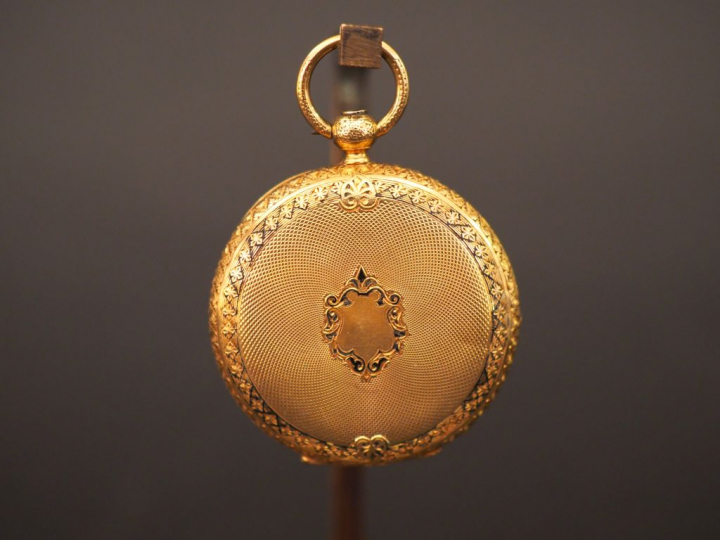 Montre de col en or jaune et émail noir. Le revers à décor de monogram