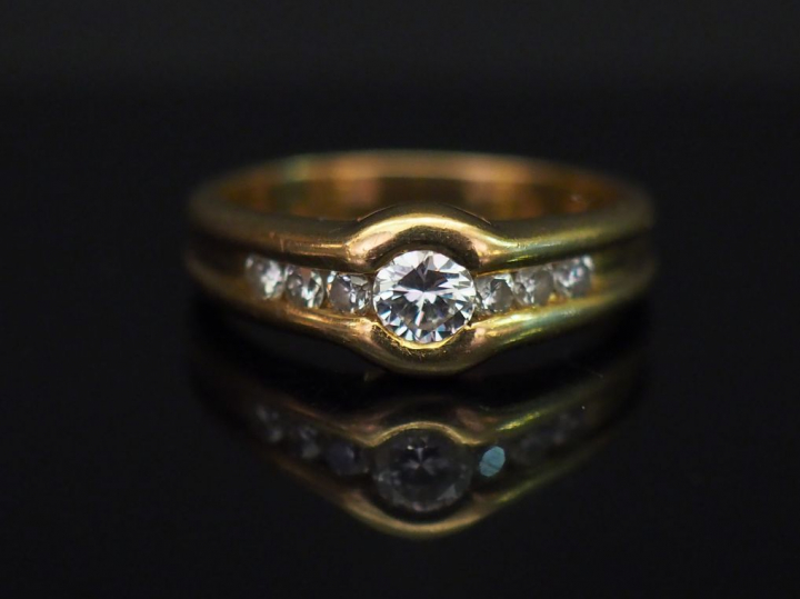 	Bague jonc en or jaune, sertie en son centre d’un diamant épaulé de s