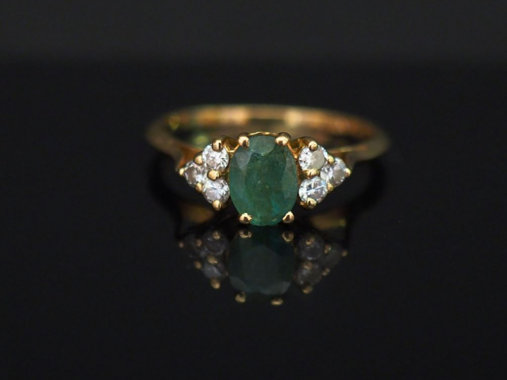 	Bague en or jaune, sertie en son centre d’une émeraude épaulée de six