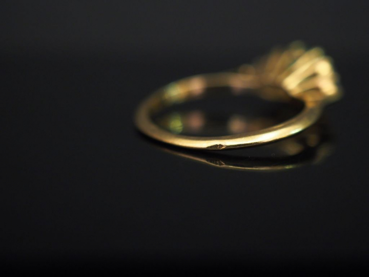 	Bague en or jaune, sertie en son centre d’une émeraude épaulée de six