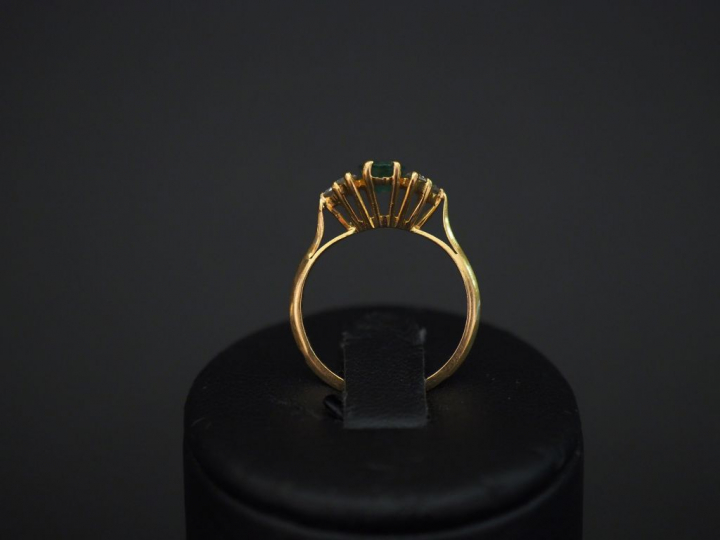 	Bague en or jaune, sertie en son centre d’une émeraude épaulée de six