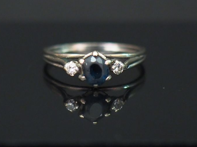 	Bague en or blanc, sertie en son centre d’un saphir épaulé de deux pe