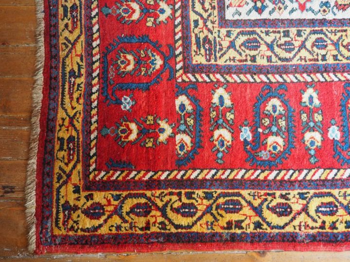 Grand tapis d'orient à fond clair et rouge. Dim. 570 x 310 cm.