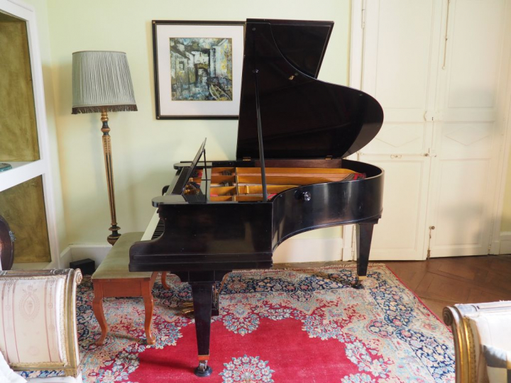 Piano quart de queue Berchstein en bois laqué noir cadre fer.
