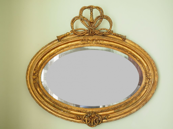 Miroir ovale de style Louis XVI, cadre en bois et stuc doré à décor de