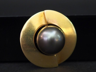 Vente aux enchères Pendentif rond en or jaune, sertie en son centre d’une perle grise. Di