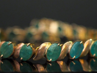 Vente aux enchères 	Bracelet articulé en or jaune 14k, serti de dix-neuf émeraudes. Long.