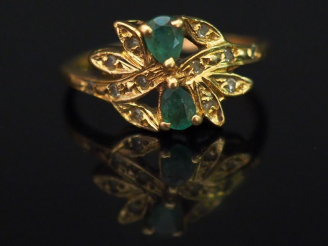 Vente aux enchères 	Bague en or jaune, sertie de deux petites émeraudes et éclats de diam