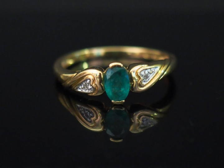 Bague en or jaune, sertie en son centre d’une émeraude épaulée de deux