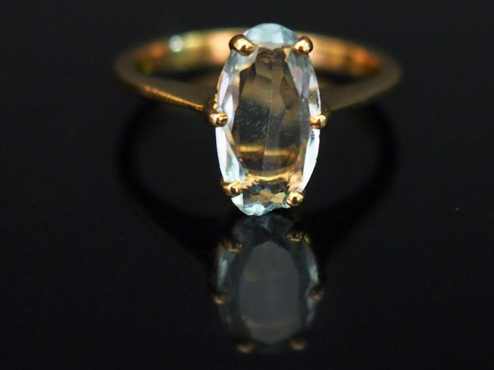 Bague en or jaune, sertie en son centre d’une pierre bleu ciel. TDD. 4