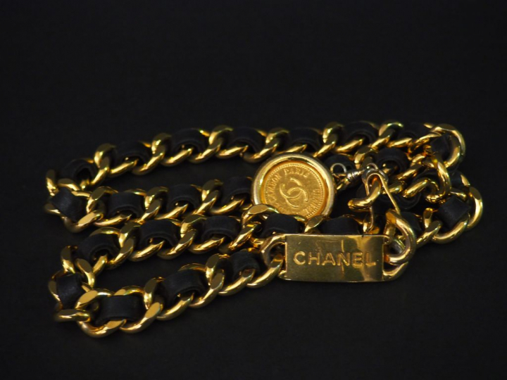 CHANEL. Ceinture en métal doré entrelacé de cuir noir, à médaille grif