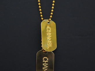 Vente aux enchères 	CHANEL Sautoir en métal doré, à décor de boules retenant deux plaques