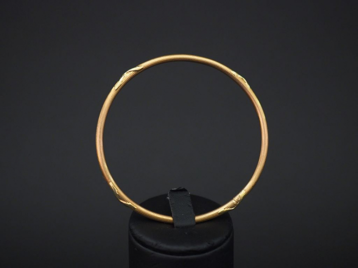 Bracelet jonc en or jaune, à décor de tiges enrubannées. Diam. 6,1 cm 