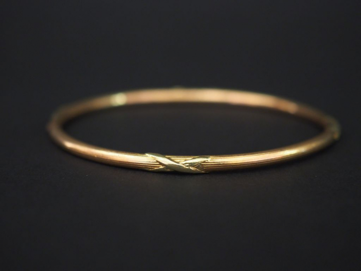 Bracelet jonc en or jaune, à décor de tiges enrubannées. Diam. 6,1 cm 