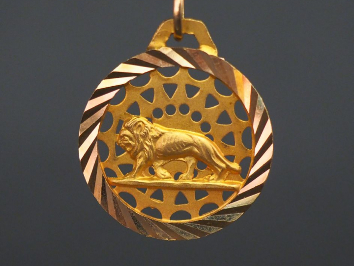 Pendentif circulaire en or jaune, à décor d’un lion sur fond ajouré. D