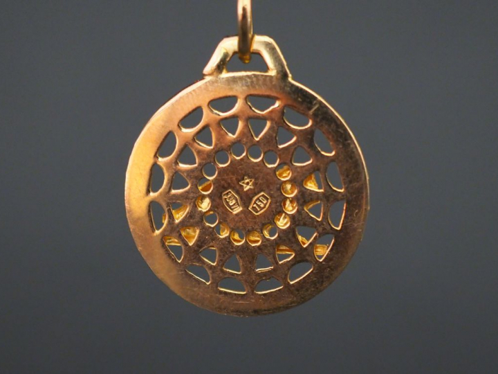 Pendentif circulaire en or jaune, à décor d’un lion sur fond ajouré. D