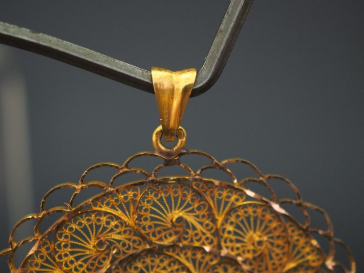 Grand pendentif circulaire en or jaune, à décor ajouré et filigrané.  