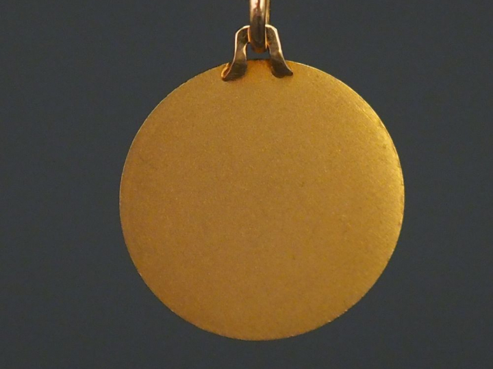 Médaille religieuse en or jaune, figurant Sainte Geneviève.  Diam. 1,8