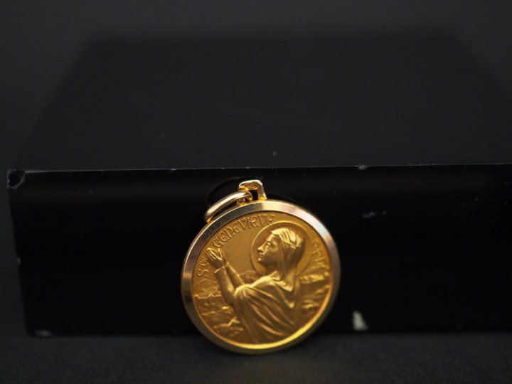 Médaille religieuse en or jaune, figurant Sainte Geneviève.  Diam. 1,8