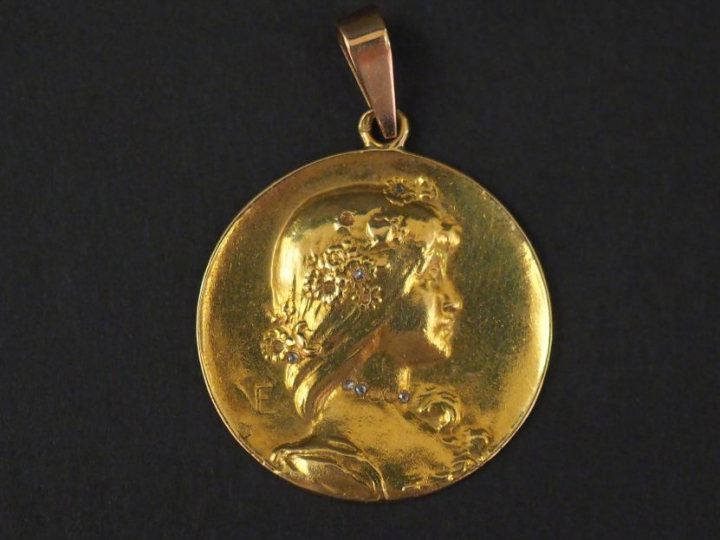 Médaille en or jaune et petits éclats de diamants, figurant une jeune 
