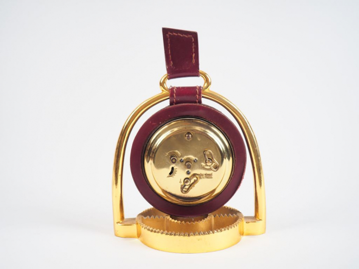 LONGCHAMP.  Pendulette en bronze et cuir en forme d'éperon.  Dim. 18 x