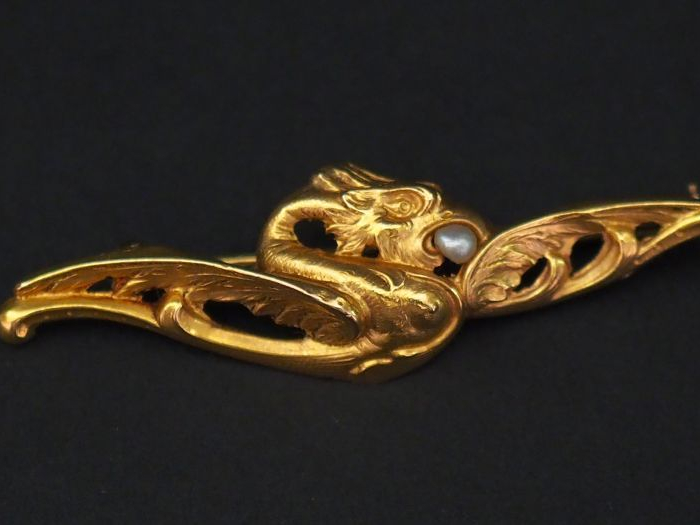 Broche en or jaune, figurant un aigle stylisé tenant dans son bec une 