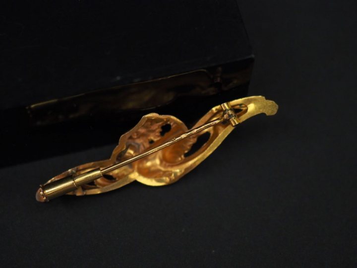 Broche en or jaune, figurant un aigle stylisé tenant dans son bec une 