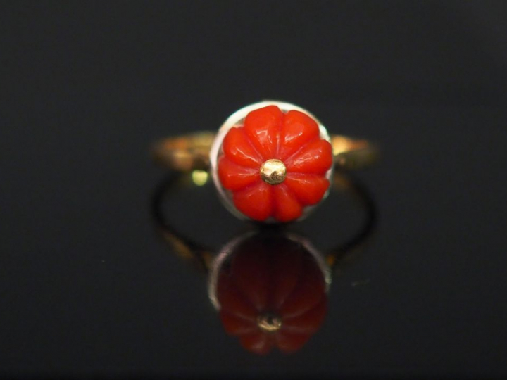 Bague en or jaune, sertie en son centre d'un corail en cabochon godron
