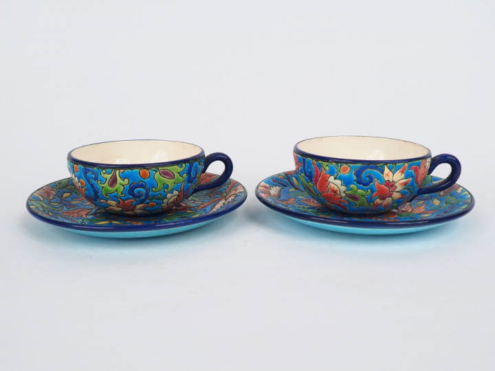 LONGWY.  Paire de tasses et sous-tasses en émaux polychromes à décor d