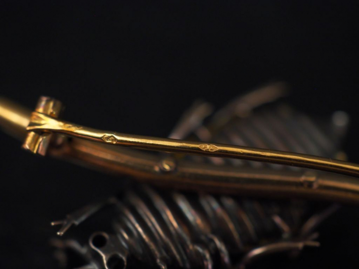 Broche en forme de scarabée posé sur une branche en or.  Le thorax ser